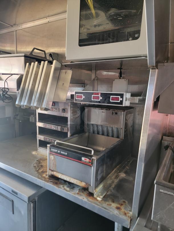 Commercial food warming station with multiple heat drawers, digital controls, and "Crisp N' Hold" branding, shows wear.