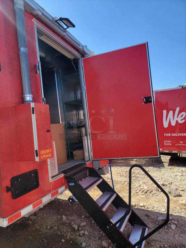 Red mobile food truck with open rear door and steps. Interior features metal shelving. Label reads "120/208 V 3 Phase."