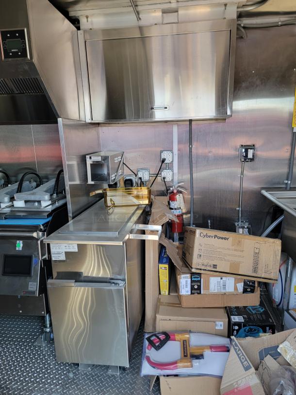 Commercial kitchen with stainless steel cabinetry, various appliances, and boxes. Visible brand labels include CyberPower and Rolfs.