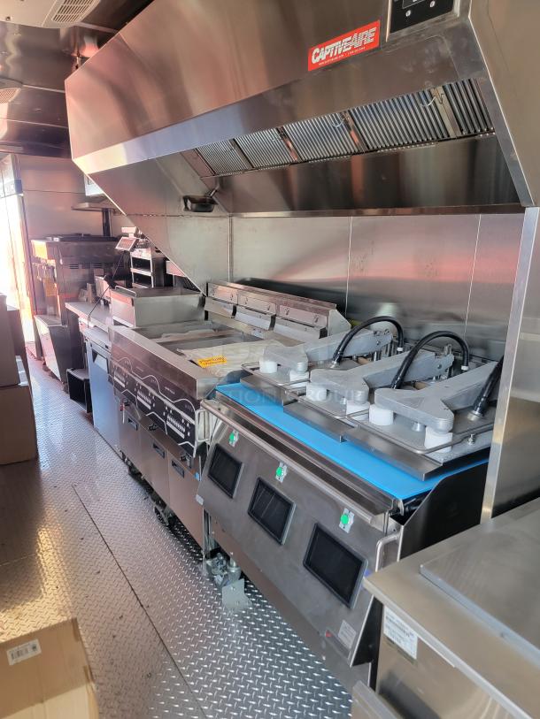 Commercial kitchen setup with CaptiveAire hood, stainless steel appliances, including grills and fryers, in excellent condition.