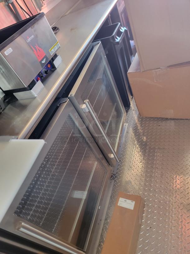 Commercial kitchen setup with a Cayenne warmer and stainless steel double-door refrigerator. Good condition.
