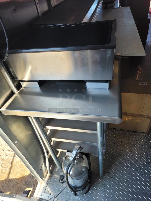 Stainless steel commercial kitchen sink with backsplash and adjustable shelving, includes mounted fire extinguisher, excellent condition.