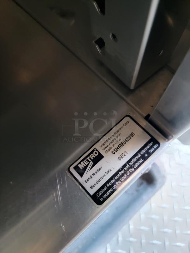 Metal shelf with Metro label, serial number C5HME042908, manufactured 09/21, featuring minor surface scratches.