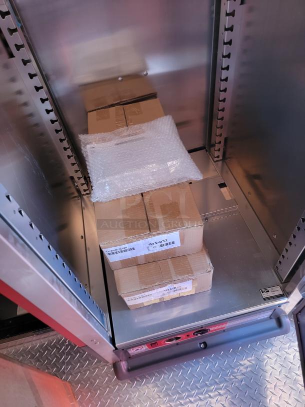 Cardboard boxes labeled "G11-032" inside a metal storage cabinet with bubble wrap on top.