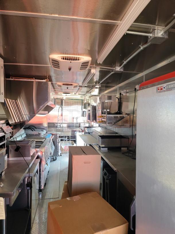Commercial kitchen trailer interior with stainless steel surfaces, appliances, and storage. Visible Metro C5 Series warming cabinet.