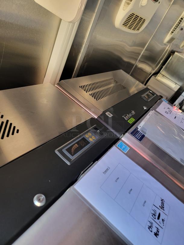 Commercial stainless steel refrigerator with control panel display, ventilation slots, and labeled freezer storage instructions.