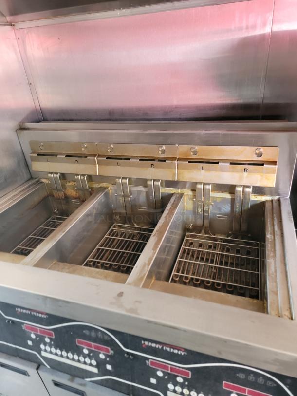 Four-bay Henny Penny deep fryer, stainless steel, digital controls. Visible wear, suitable for commercial kitchens.