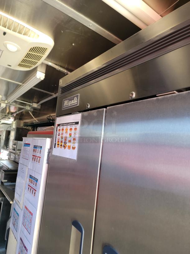 Commercial Minali stainless steel refrigerator, dual doors, good condition, with instruction sheets affixed to the front.