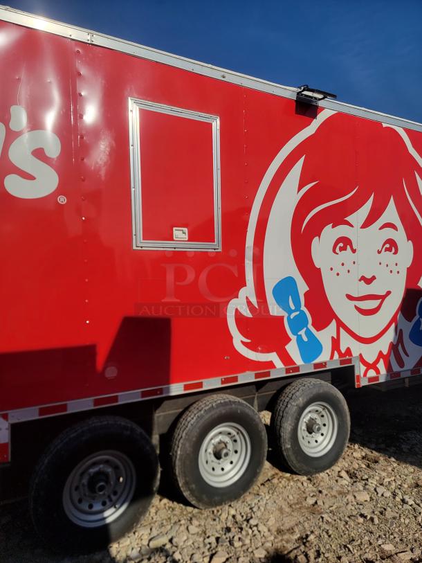 Red food trailer with Wendy's logo and service window, triple axle. Bright, clean exterior indicates good condition.