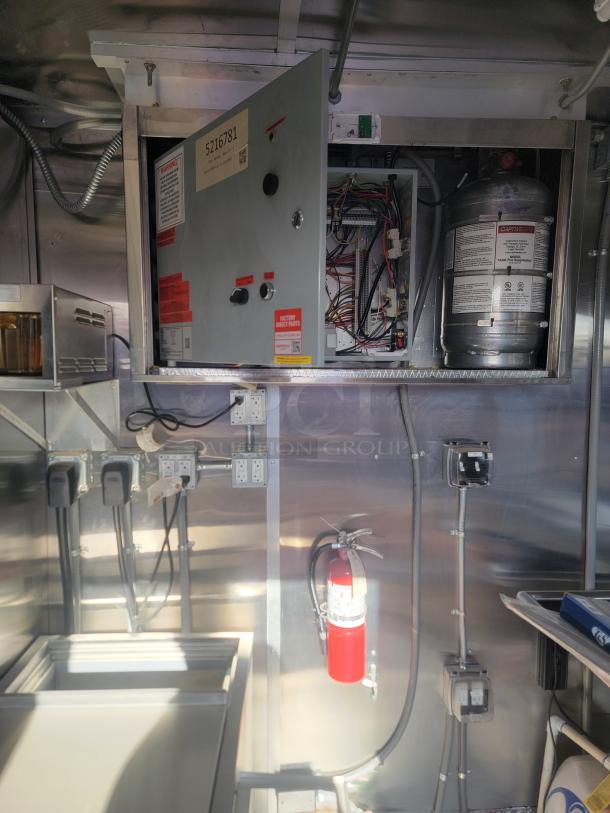 Fire suppression system in stainless steel kitchen. Open control panel with wiring visible. Tags with serial number 5216781.