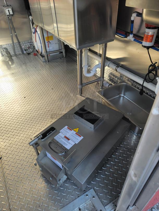 Commercial kitchen equipment in stainless steel, featuring diamond plate flooring. Visible labels provide safety and operational info.