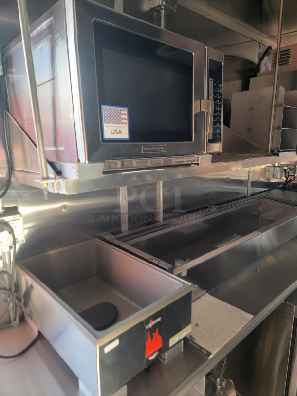 Industrial Menumaster microwave oven, stainless steel finish, with USA label, in commercial kitchen setting.