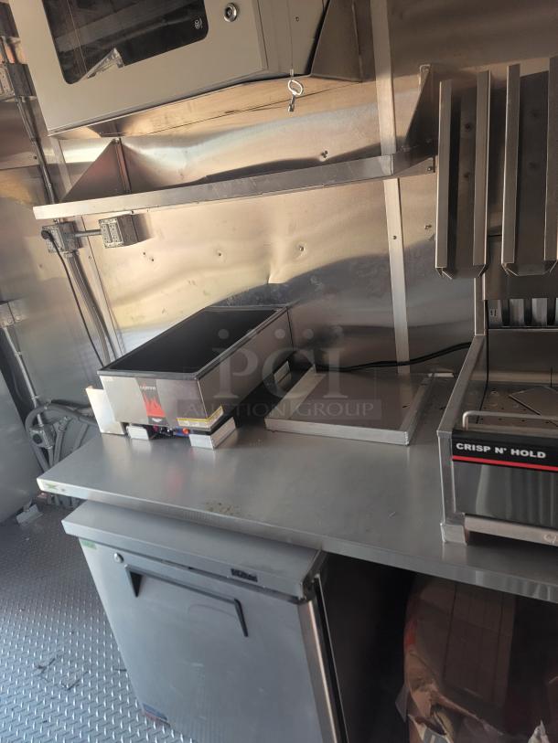 Commercial kitchen setup with a Crisp N' Hold system, stainless steel surfaces, and under-counter storage. Good condition.