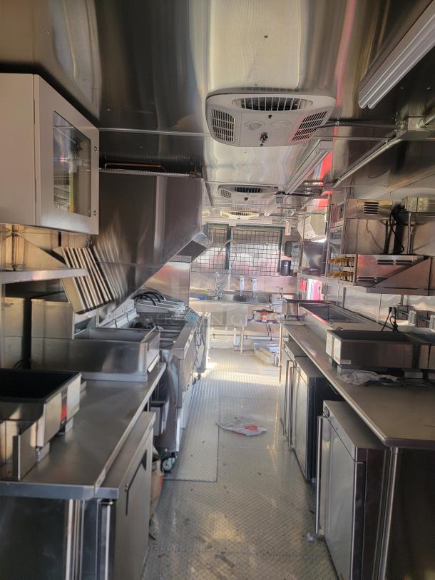 Mobile kitchen interior with stainless steel appliances, including grills, ovens, and storage units. Clean and modern design.