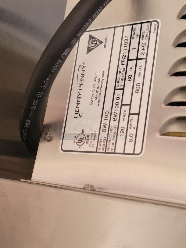 Henny Penny appliance label showing model BW100.01, 120 volts, 600 watts, serial FB2111037, made in USA.