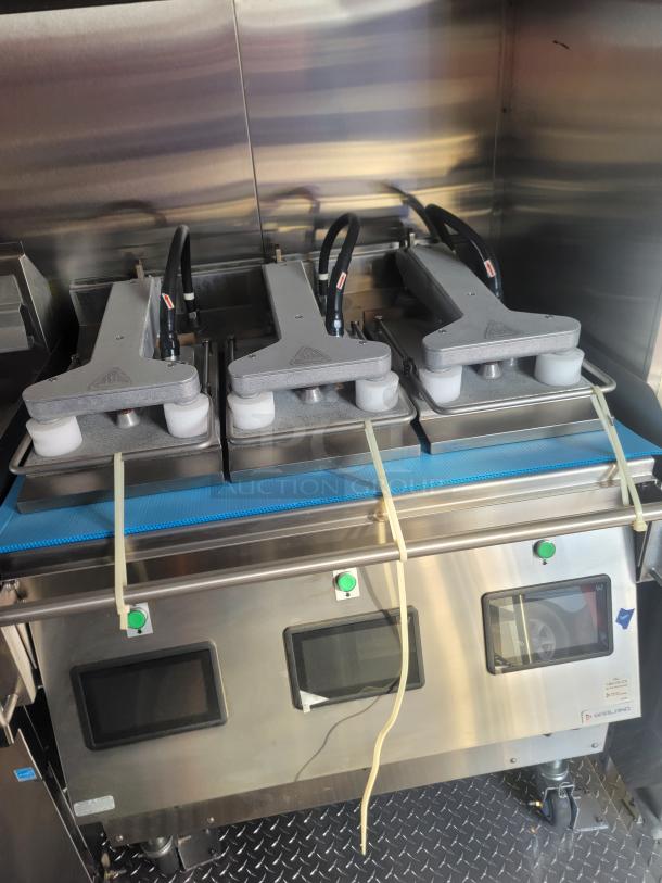 Commercial food processing equipment with three metal clamps, touch screens, tubing, and a stainless steel exterior.