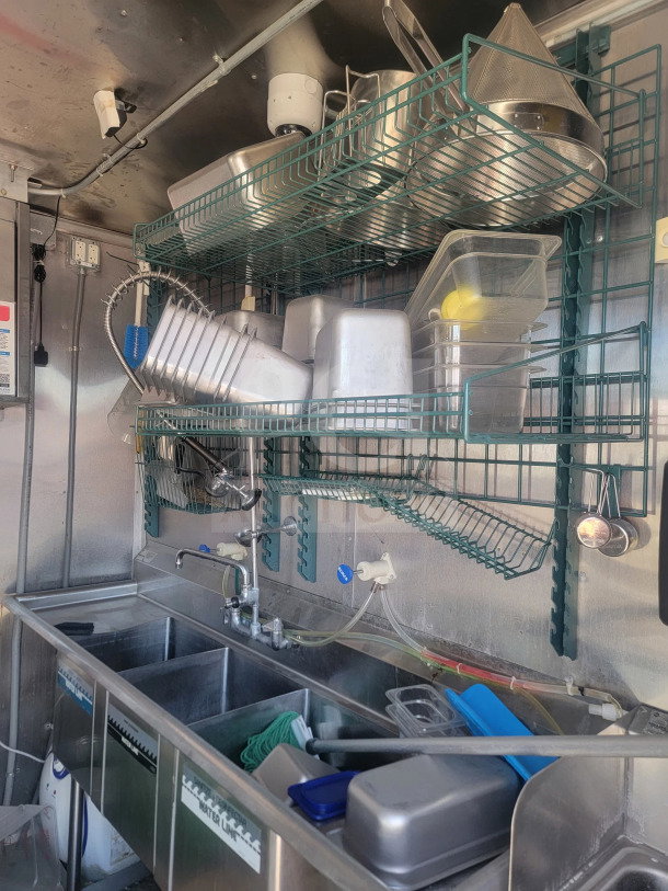 2021 Rock Solid Cargo 8.5' x 28' mobile kitchen interior, featuring triple sink and storage racks, in excellent condition.
