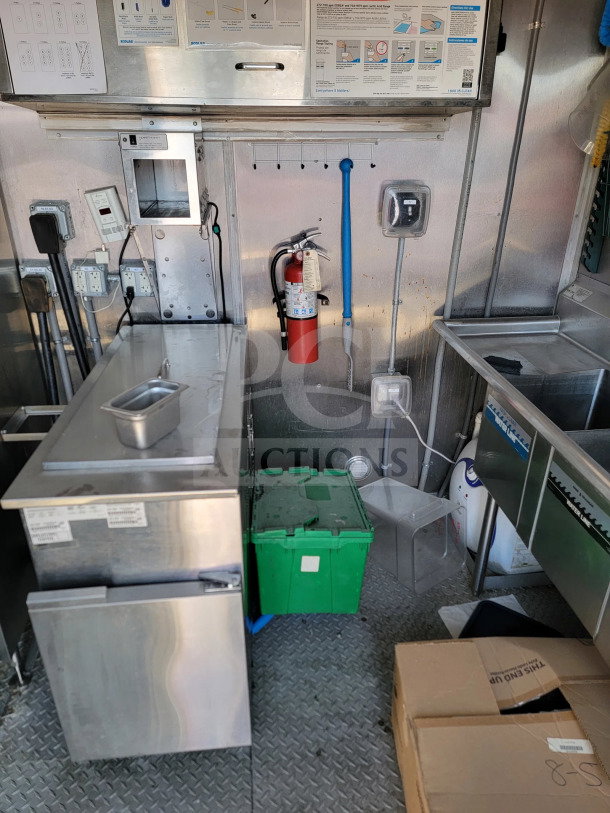 2021 Rock Solid Cargo 8.5' x 28' mobile kitchen trailer interior. Features CaptiveAire hood, stainless counters, and fire extinguisher.