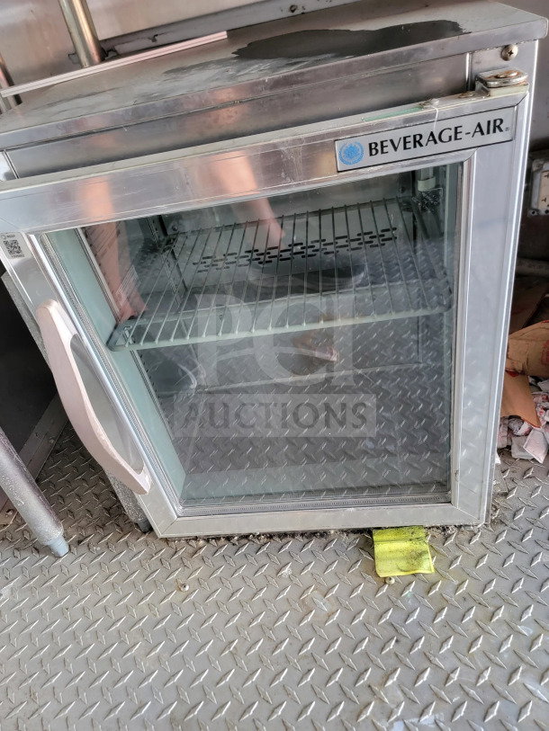 Beverage-Air refrigeration unit inside 2021 Rock Solid Cargo mobile kitchen trailer. Stainless steel exterior, glass door, wire shelf.
