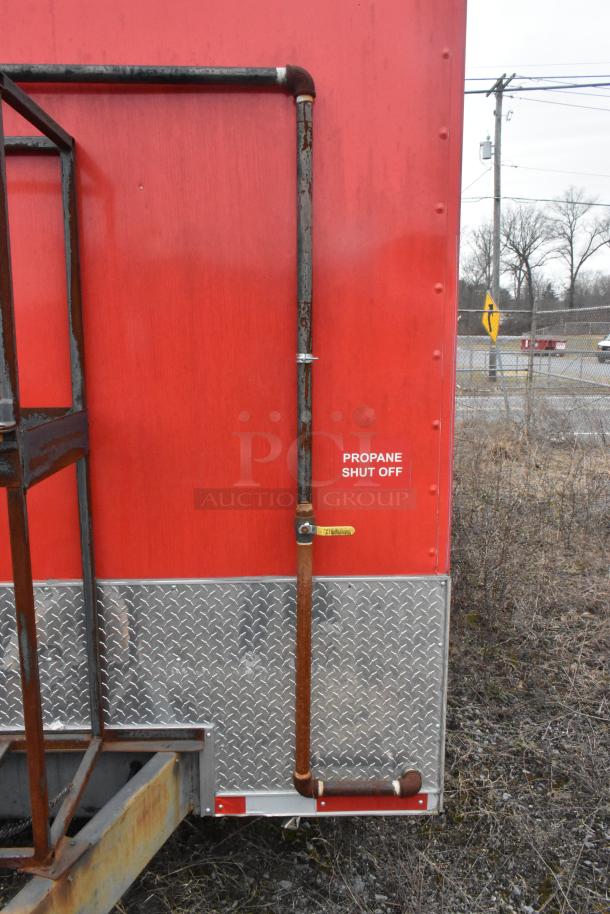 Red mobile kitchen trailer exterior featuring propane shut-off valve and diamond plate paneling.