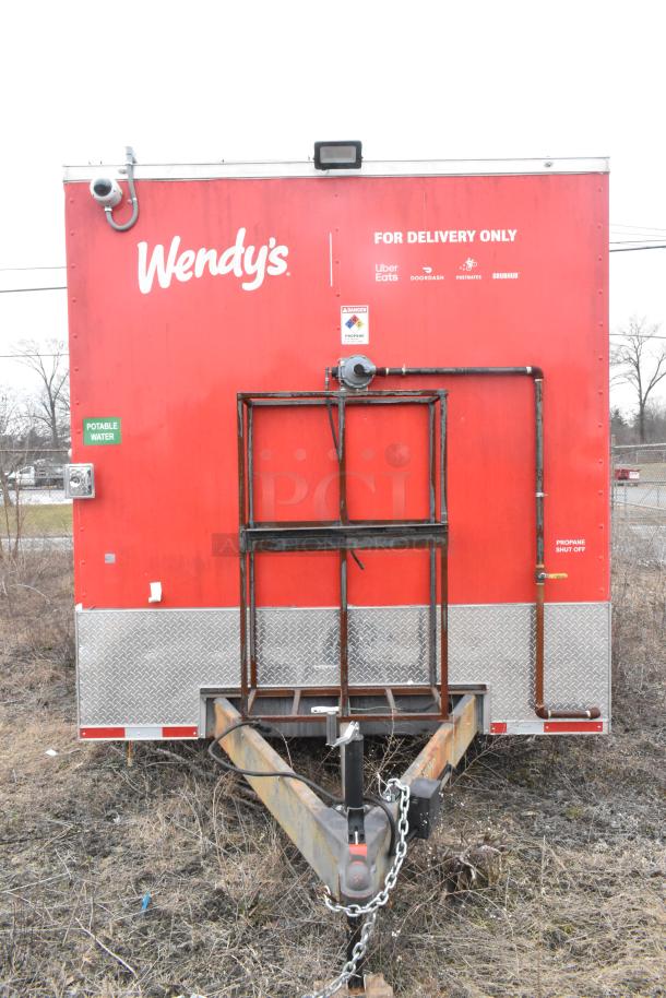 8.5' x 28' Wendy's mobile kitchen trailer, new, red exterior, labeled for delivery, propane setup, and water access.