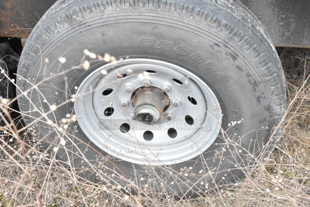 Close-up of a tire on an 8.5' x 28' mobile kitchen trailer, featuring triple axle support.