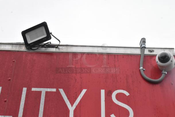 Red Wendy's mobile kitchen trailer exterior with LED floodlight, security camera, and partial text visible.