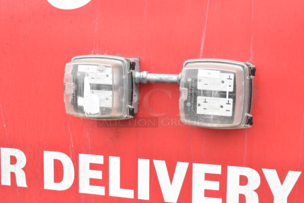 Exterior of a mobile kitchen trailer showing two weatherproof electrical outlets outlined against a red background.