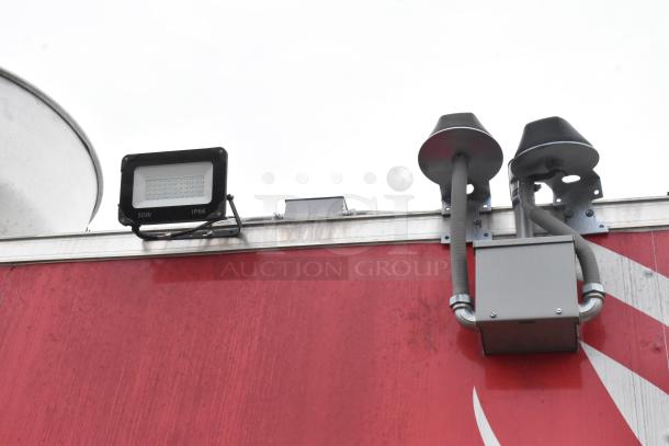 Exterior detail of a Wendy's mobile kitchen trailer, showing rooftop lighting and ventilation. Red siding visible.
