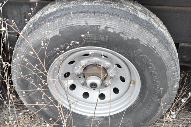 Tire on a fully equipped Wendy's mobile kitchen trailer, featuring Goodride branding and visible wear, set in a grassy area.