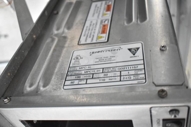 Metal surface with label for Henny Penny MPC-1L, showing electrical specifications: 120 volts, 60 Hz, 110 watts, 0.92 amps.