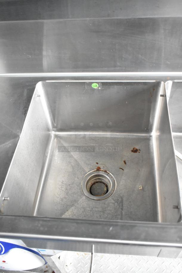 Stainless steel sink inside Wendy's mobile kitchen trailer, showing minor rust and wear.