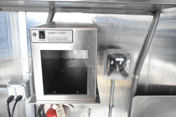 Henny Penny kitchen appliance inside a mobile kitchen trailer, stainless steel, new condition, power switches visible.