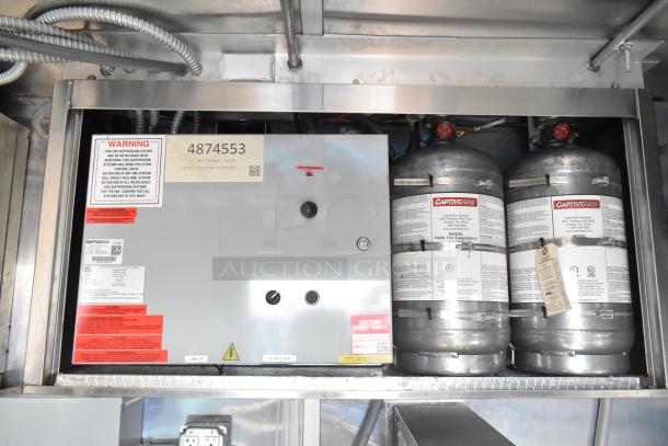 CaptiveAire fire suppression system in Wendy's mobile kitchen trailer, features warning label and model details, brand new.