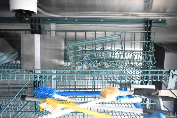 Interior of Wendy's mobile kitchen trailer with shelving, cleaning brushes, and storage baskets.