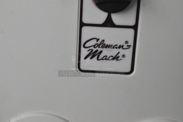 Close-up of Coleman Mach A/C logo on white surface of Wendy's Mobile Kitchen Trailer.