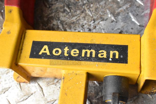 Yellow Aoteman tool with black label, placed on a textured metal surface, some dirt visible.