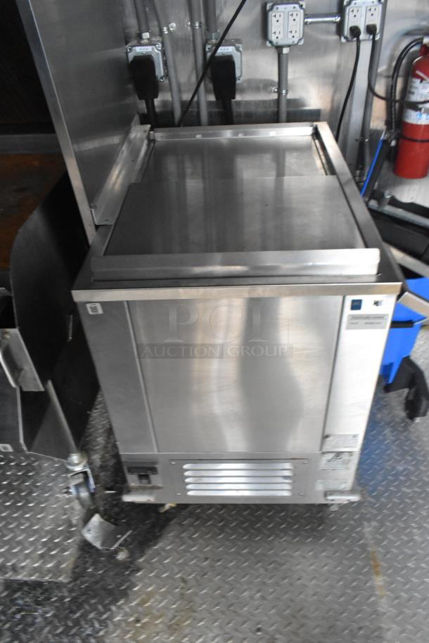 Stainless steel commercial kitchen equipment inside a new mobile kitchen trailer, showing pristine condition and utility outlets.