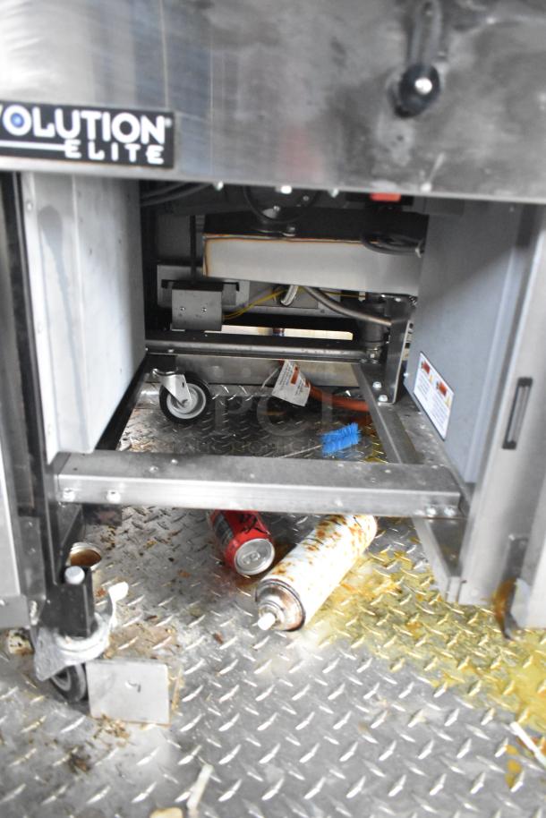 Interior view of Wendy's Mobile Kitchen Trailer showing a Henny Penny Evolution Elite gas fryer with casters, cans, and a brush on the floor.
