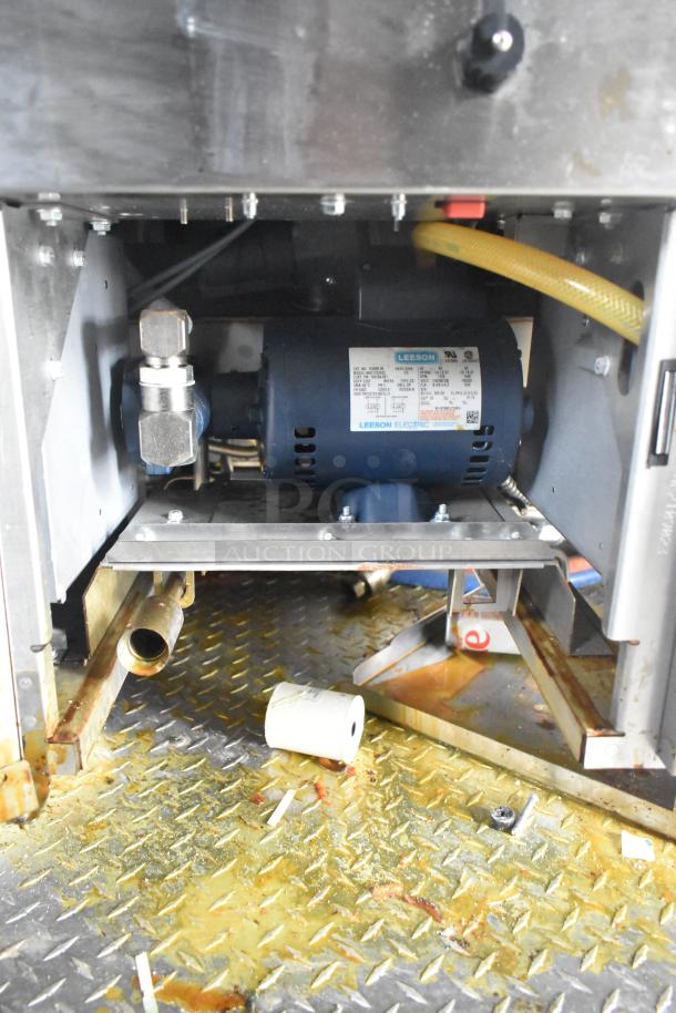 Interior view of Wendy's mobile kitchen trailer showing Leeson electric motor and plumbing on diamond plate flooring.