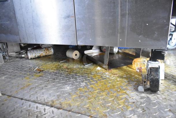 Interior view of a mobile kitchen trailer with visible debris and greasy residue on the metal floor.