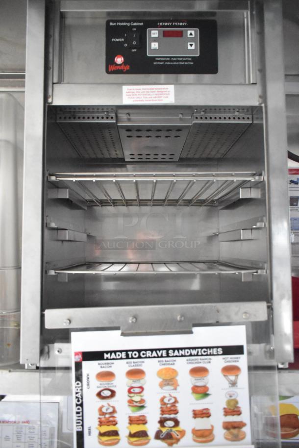 Wendy's mobile kitchen trailer interior featuring a Henny Penny bun holding cabinet with controls and a sandwich build card.