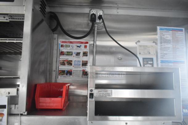 Interior view of a Wendy's mobile kitchen trailer showing electrical outlets, a red storage bin, and equipment instructions.