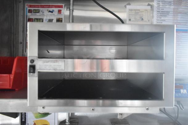 Stainless steel kitchen appliance inside a mobile kitchen trailer, showing the interior and control panel.
