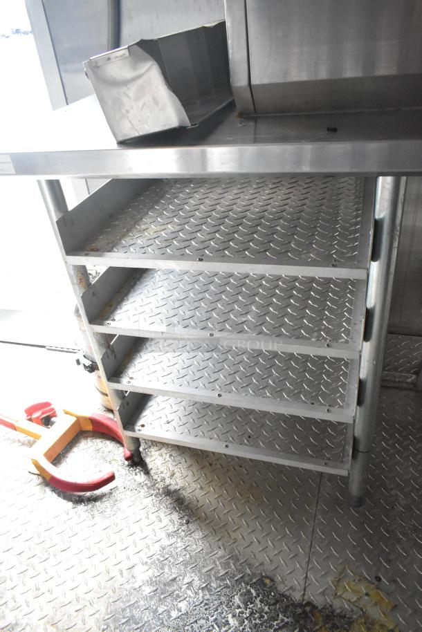 Interior of a Wendy's Mobile Kitchen Trailer showing diamond plate flooring and metal shelving, indicating durable construction.
