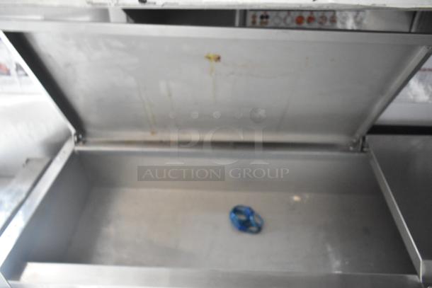 Stainless steel compartment interior of Wendy's Mobile Kitchen Trailer, featuring clean surfaces, open lid, and blue object inside.