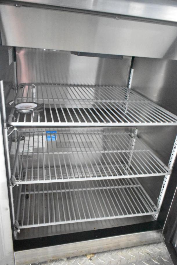 Interior of commercial refrigeration unit inside a mobile kitchen trailer, featuring metal shelving and temperature gauge.