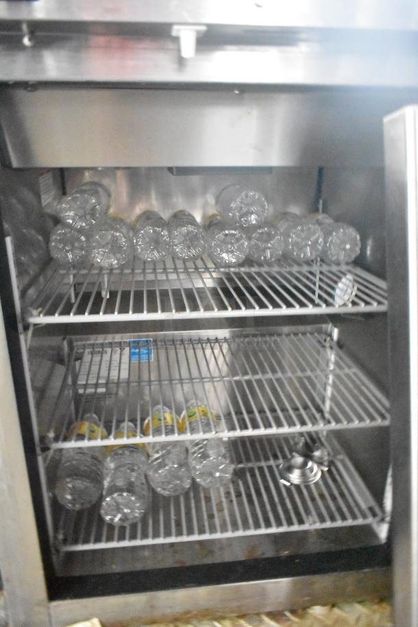 Interior of a mobile kitchen trailer refrigeration unit with wire shelves holding empty plastic bottles.