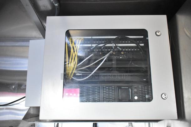 CyberPower power control unit inside a secured panel, featuring organized wiring and network components, part of mobile kitchen setup.