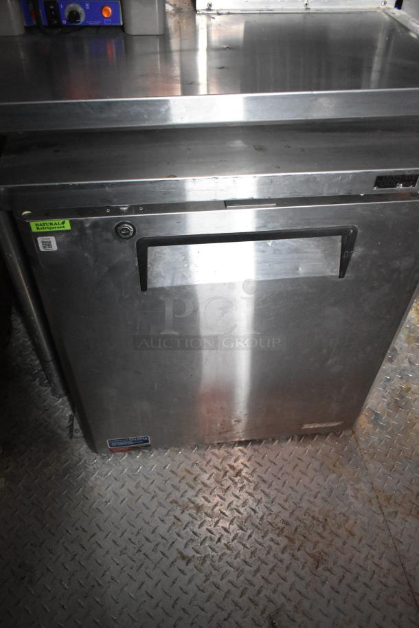 Stainless steel refrigeration unit in mobile kitchen trailer, features natural refrigerant label.